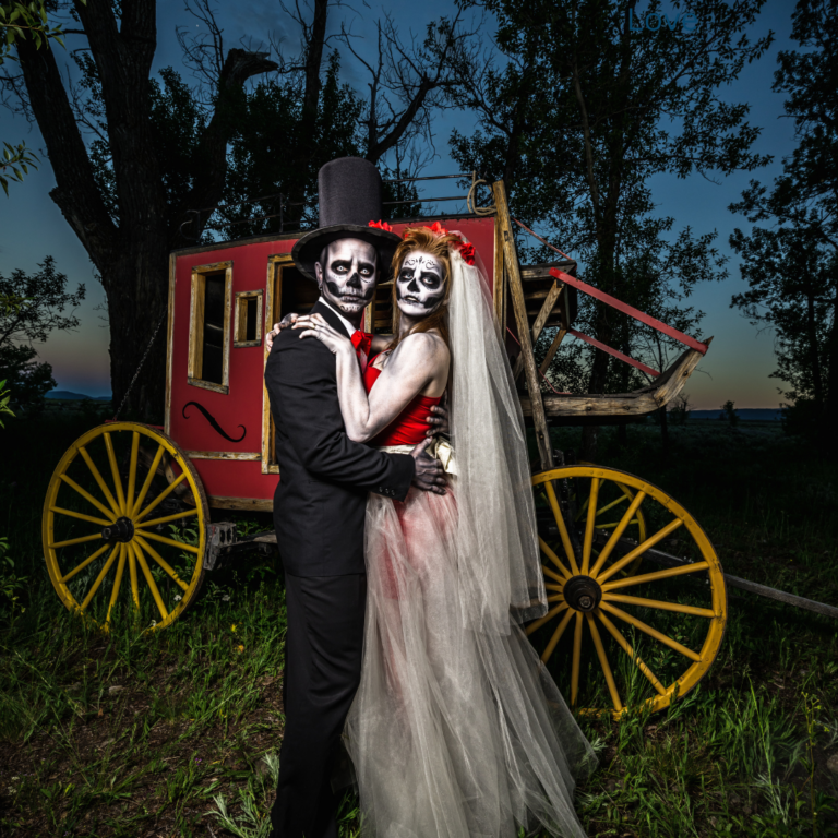 Halloween Wedding couple in front of a red and gold carriage at an East Texas wedding venue.