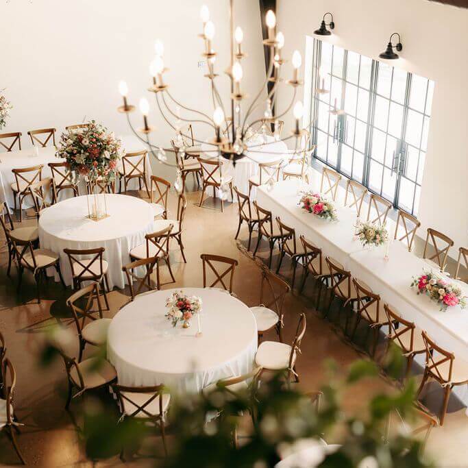 Outdoor wedding ceremony with wooden chairs and floral arch near North Texas countryside.