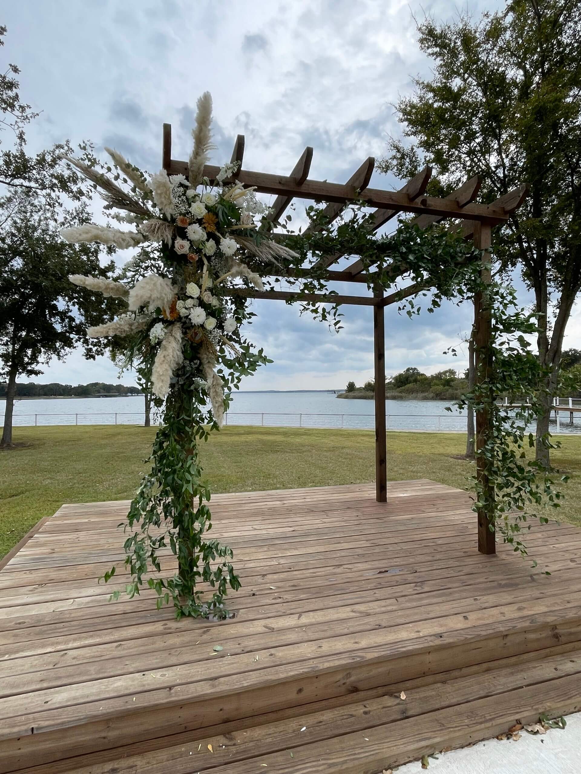 Lakeside gazebo wedding ceremony setup at Lakefront Acres near Fairfield TX with white chairs, floral arch, and panoramic lake view.
