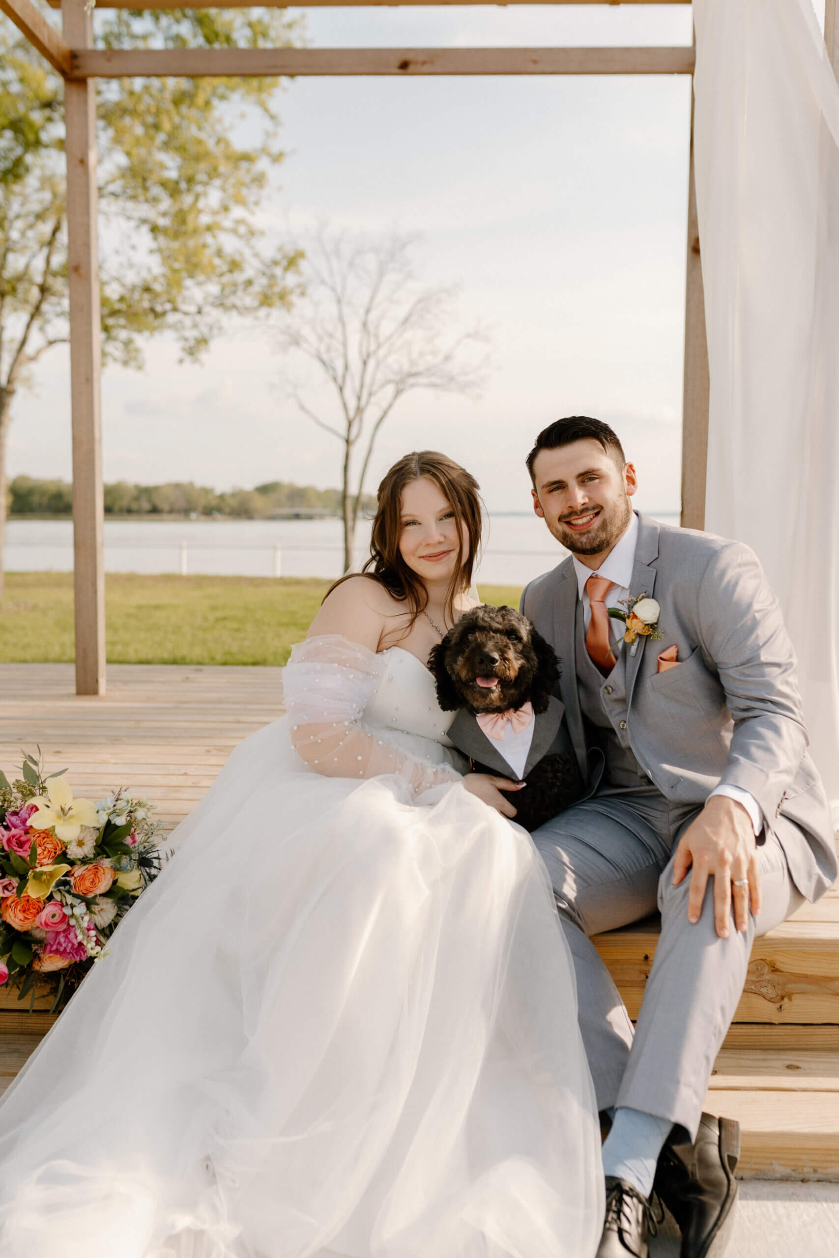 Bride and groom celebrating outdoors during sunset at a lakeside wedding venue while planning their wedding timeline and checklist for the big day.