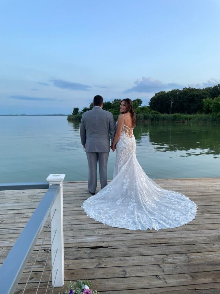 Bride and groom standing lakeside at Lakefront Acres Wedding & Event Venue in Texas.