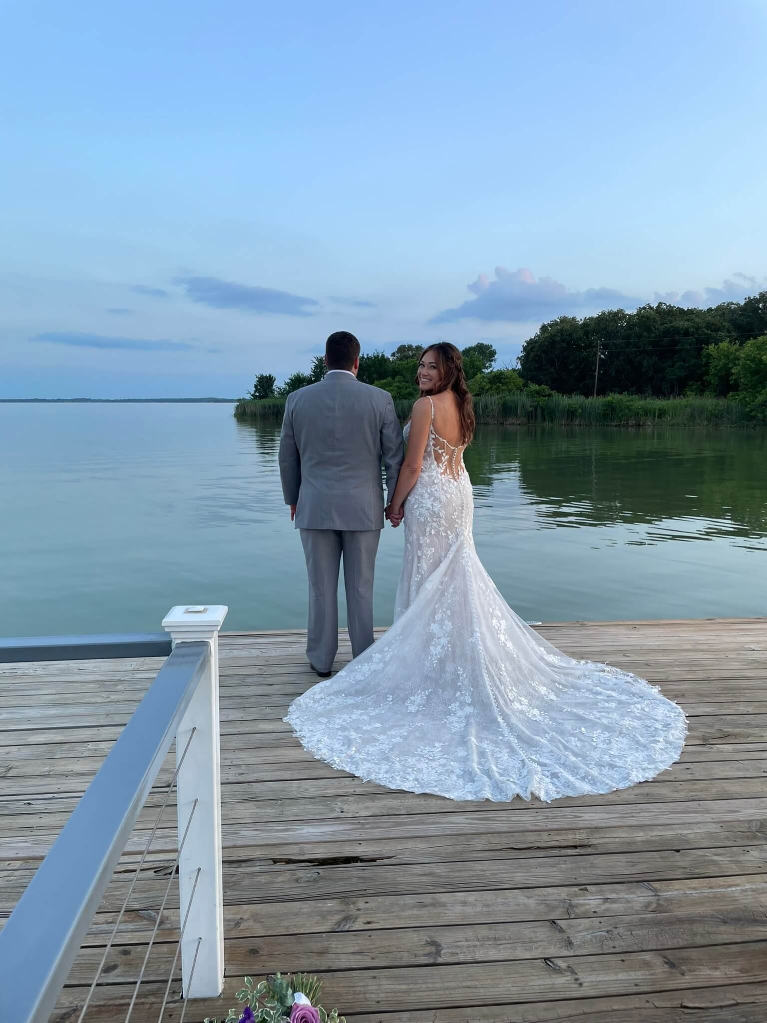 Bride and groom standing lakeside at Lakefront Acres Wedding & Event Venue in Texas.